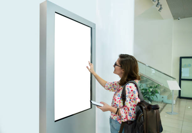 woman with phone uses self service desk with touch screen