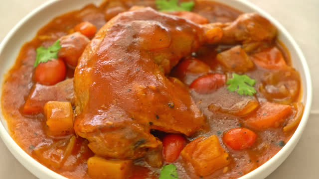 homemade chicken stew with tomatoes, onions, carrot and potatoes on plate